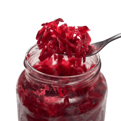 Sauerkraut A close-up of a spoonful of vibrant red sauerkraut being lifted from a glass jar. The shredded fermented cabbage has a glossy texture, showing its pickled freshness and bold color.